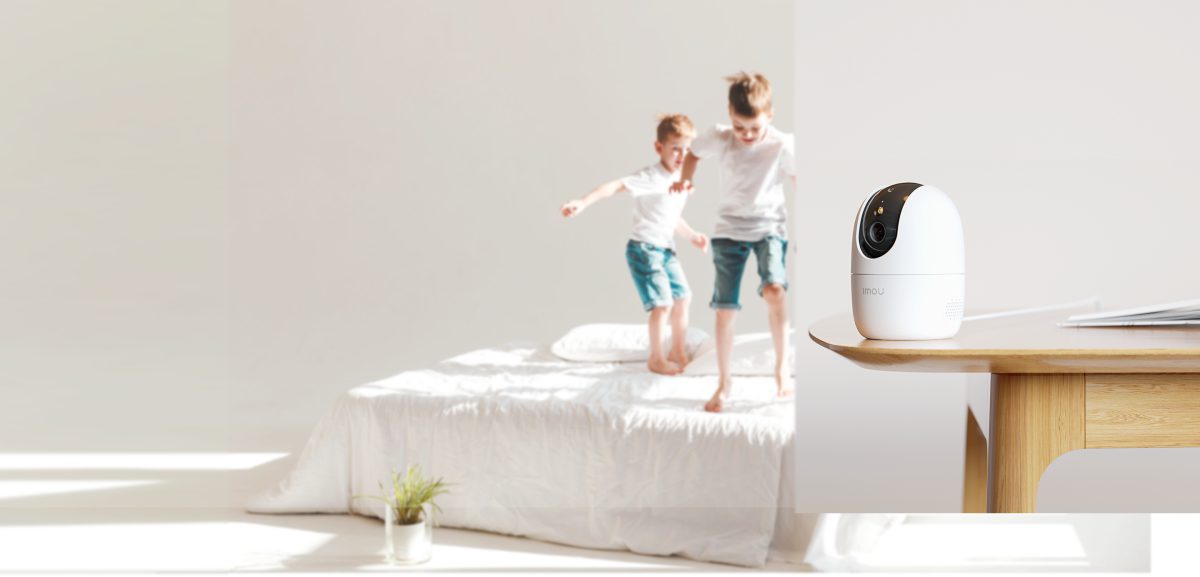 Camera Imou Ranger 2 Pro 3MP đặt trên bàn cạnh giường, hai bé đang chơi đùa